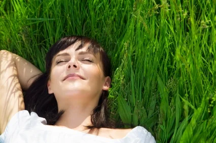 A young woman reclining in grass, rested after sleep apnea treatment in Pearland.